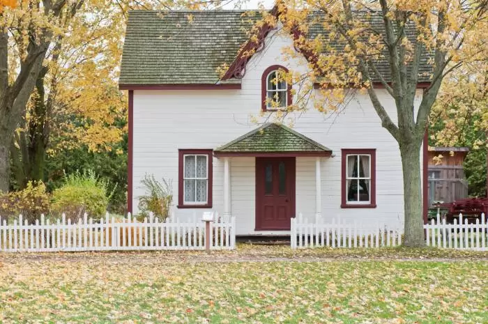 white house with red trim surrounded by autumn leaves